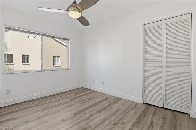 a view of empty room with wooden floor and fan