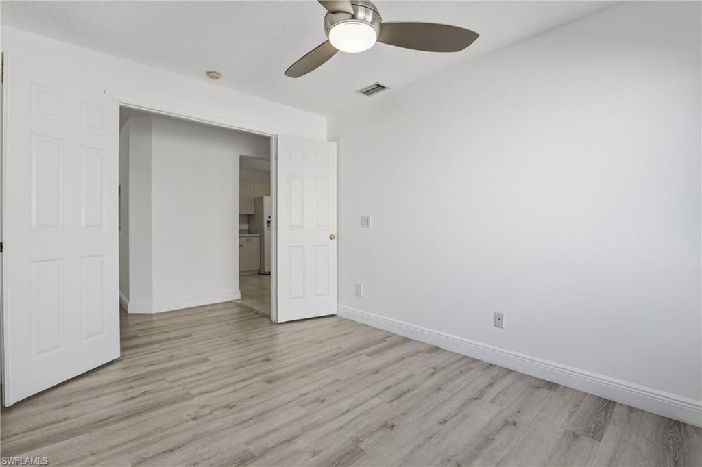7762 Jewel Lane, Unit 201 Naples, FL 34109 - Photo 26 of 39 an empty room with wooden floor chandelier fan and closet area