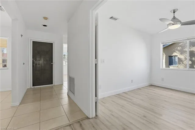 a view of an empty room with wooden floor and a ceiling fan