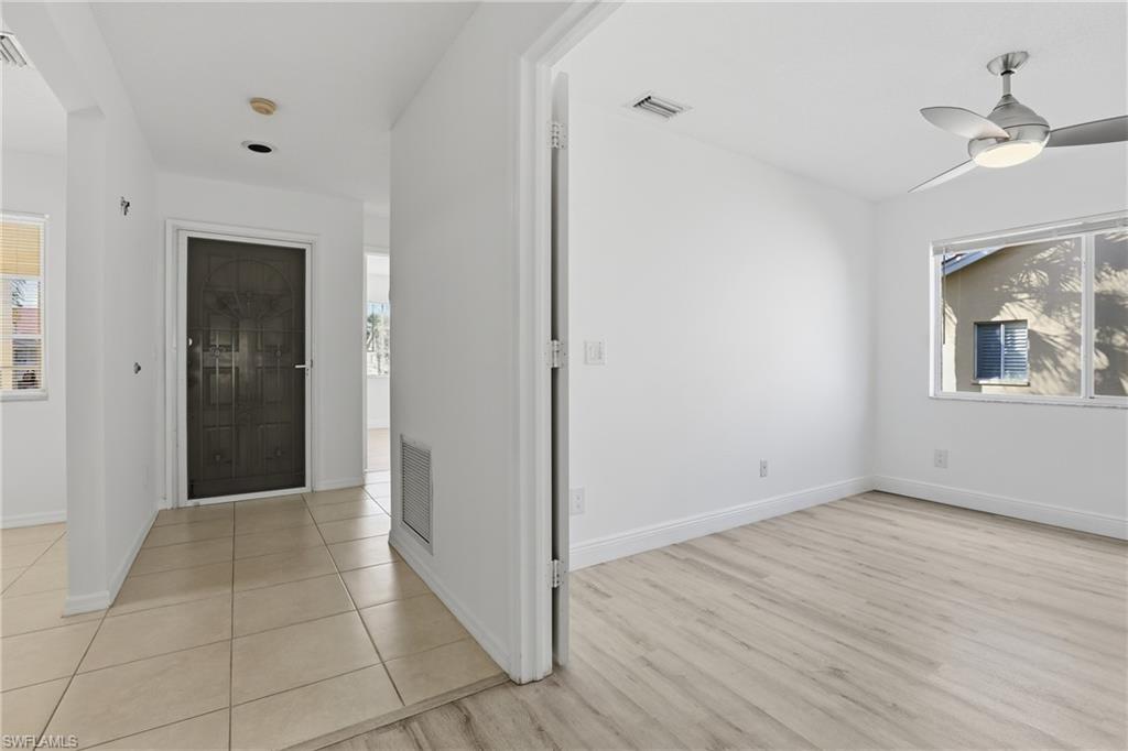 7762 Jewel Lane, Unit 201 Naples, FL 34109 - Photo 8 of 39 a view of an empty room with wooden floor and a ceiling fan