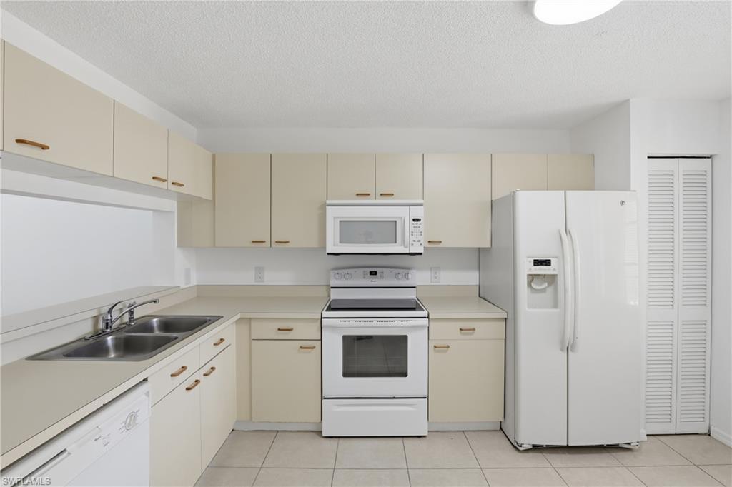 7762 Jewel Lane, Unit 201 Naples, FL 34109 - Photo 9 of 39 a kitchen with white cabinets and white appliances