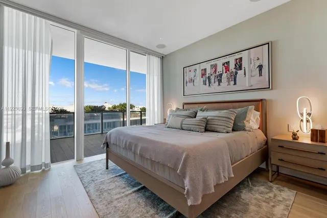a bedroom with a bed painting on wall and a large window