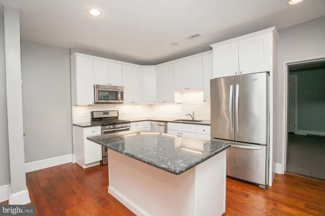 a kitchen with stainless steel appliances granite countertop a refrigerator a stove a sink a microwave a dining table and chairs