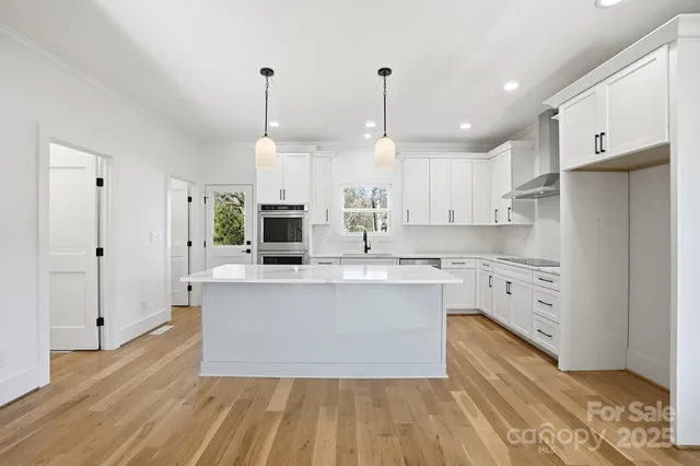 a large kitchen with cabinets wooden floor and stainless steel appliances