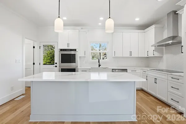 a kitchen with kitchen island white cabinets and stainless steel appliances