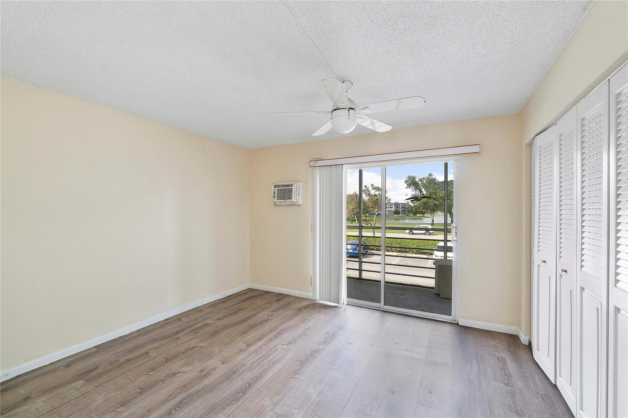 358 Dorset I, Unit 358 Boca Raton, FL 33434 - Photo 8 of 12 an empty room with wooden floor fan and windows