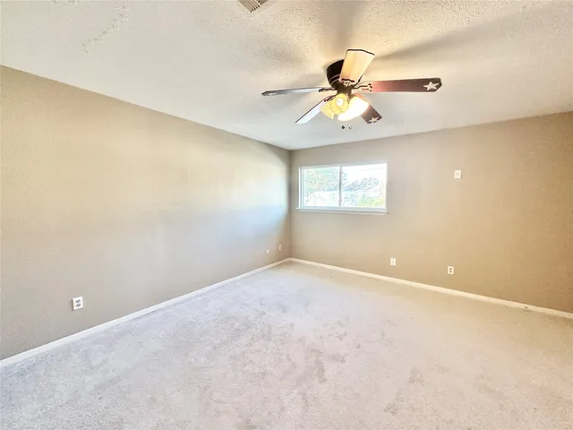 an empty room with windows and fan chandelier fan