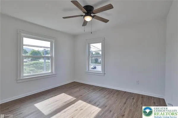 a view of an empty room with window and wooden floor