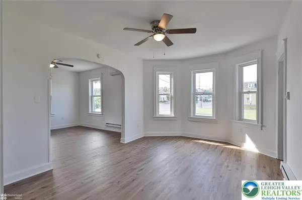a view of an empty room with a window and wooden floor