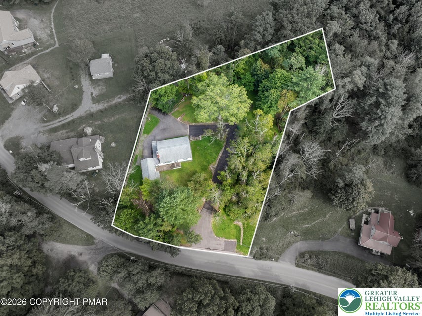 An aerial perspective showcases the generous property boundaries nestled among mature woodlands.