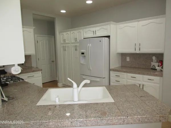 a kitchen with stainless steel appliances granite countertop a sink a stove and white cabinets