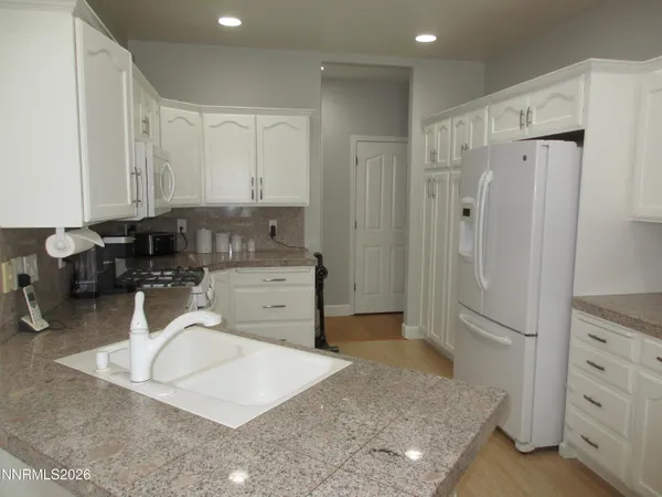 a kitchen with granite countertop a sink a stove and a refrigerator