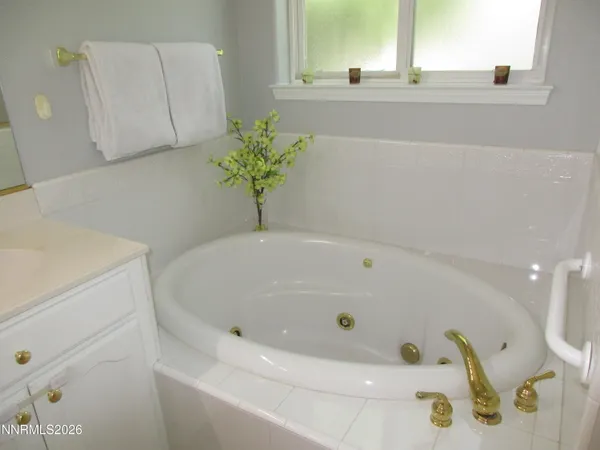 a bathroom with a granite countertop tub shower vanity and a sink