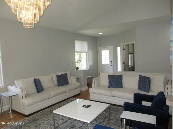 a living room with couches a coffee table a flat screen tv and a large window