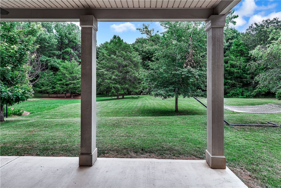 144 Buckland Drive Anderson, SC 29621 - Photo 26 of 48 A deep covered porch overlooks a verdant, expansive yard framed by mature trees.