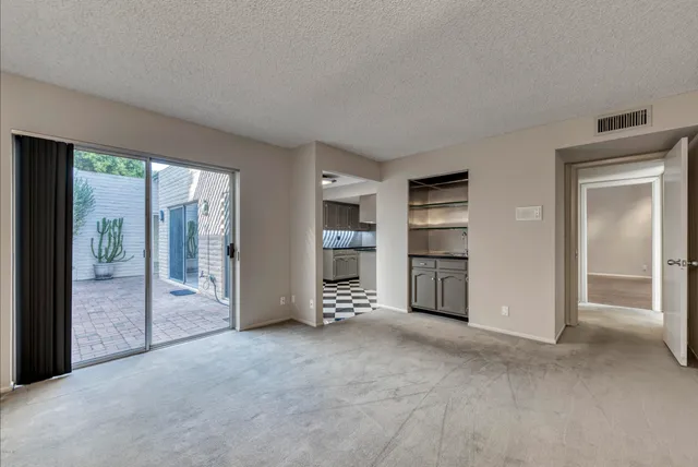 a view of an empty room with a window and a kitchen