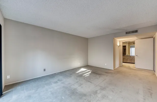 a view of an empty room with closet and a window