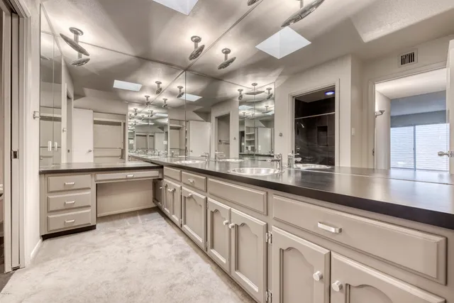 a large white kitchen with kitchen island a large counter space a sink and stainless steel appliances