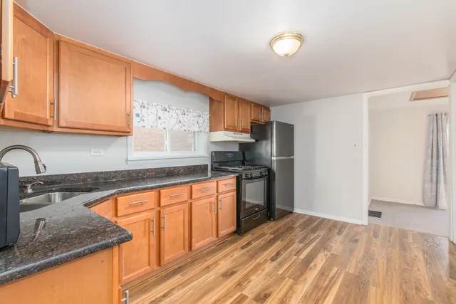 a kitchen with granite countertop a sink stove and cabinets