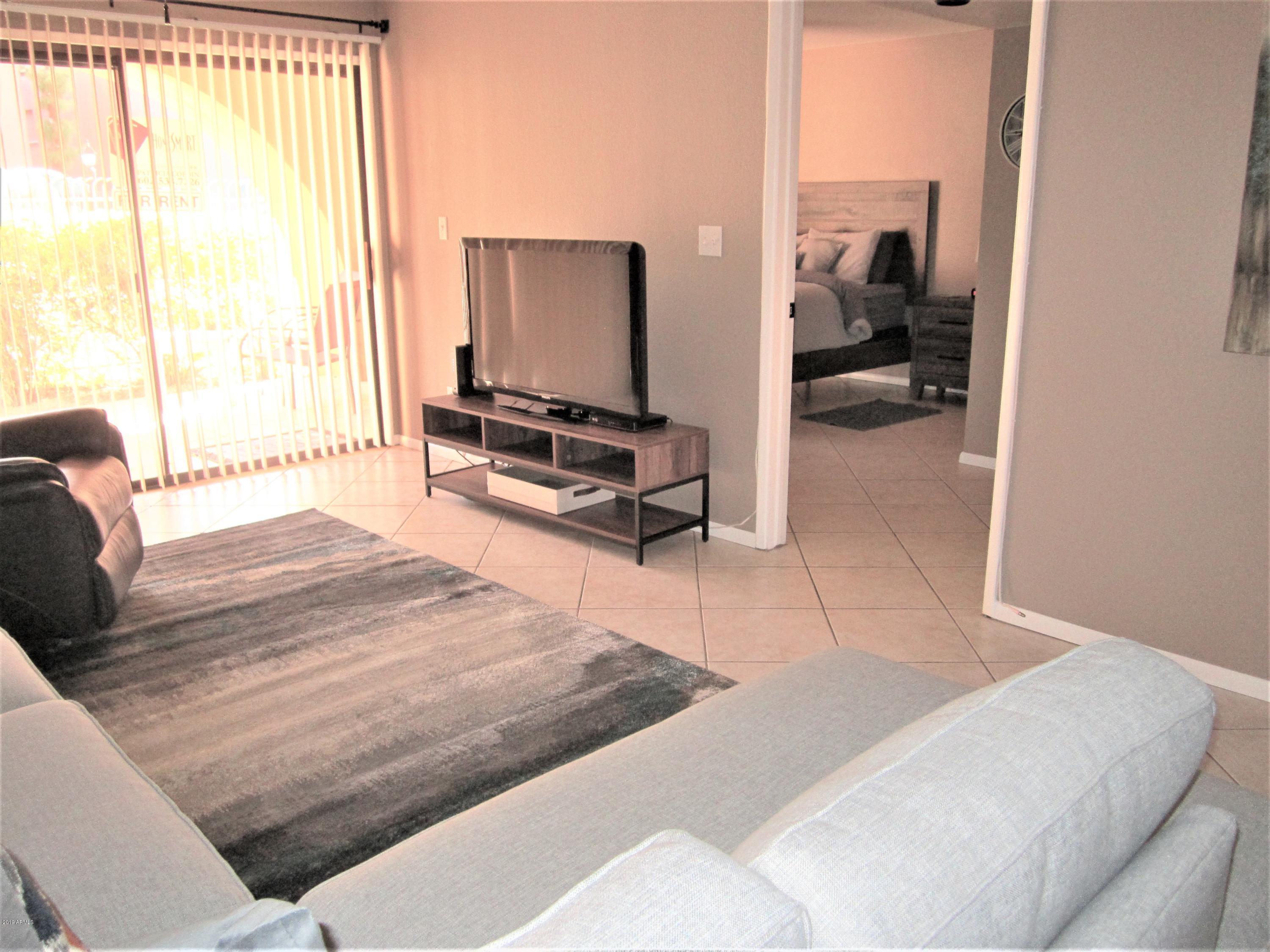 4303 East Cactus Road, Unit 116 Phoenix, AZ 85032 - Photo 7 of 35 a living room with furniture a flat screen tv and a large window