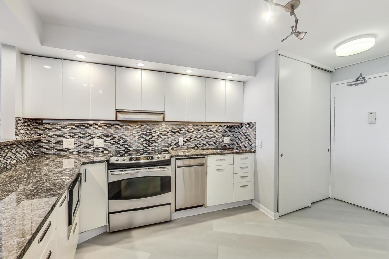 300 North State Street, Unit 4308 Chicago, IL 60654 - Photo 9 of 32 a kitchen with granite countertop white cabinets and white stainless steel appliances