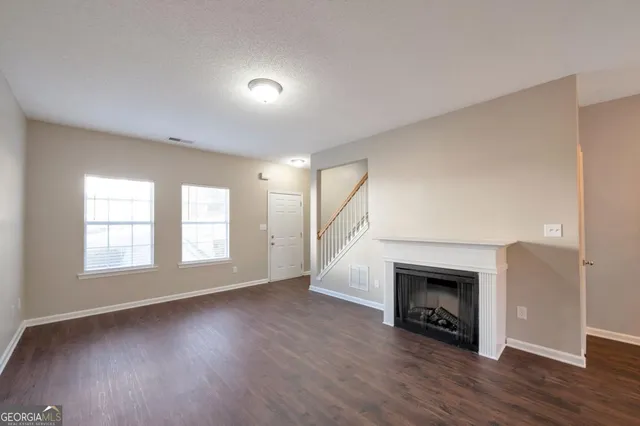 an empty room with wooden floor fire place and windows