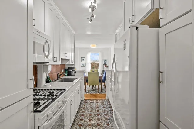 a kitchen that has a lot of cabinets a sink and wooden floor