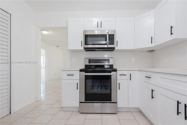 a kitchen with white cabinets and stainless steel appliances