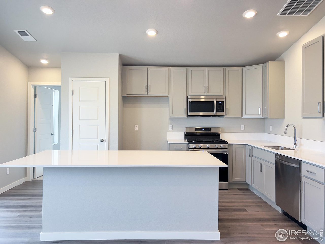 533 Bridger Avenue Fort Lupton, CO 80621 - Photo 3 of 9 a kitchen with granite countertop white cabinets and stainless steel appliances