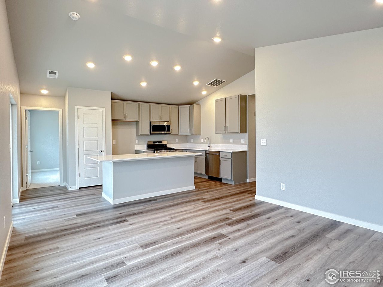 533 Bridger Avenue Fort Lupton, CO 80621 - Photo 5 of 9 a large kitchen with kitchen island a sink wooden floor and stainless steel appliances