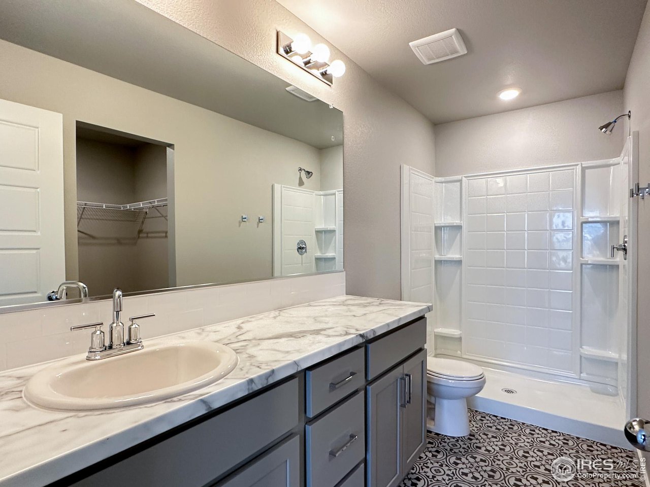 533 Bridger Avenue Fort Lupton, CO 80621 - Photo 8 of 9 a bathroom with a granite countertop sink a toilet a mirror and shower