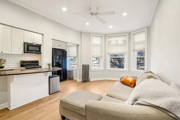 a living room with stainless steel appliances furniture a flat screen tv and a window