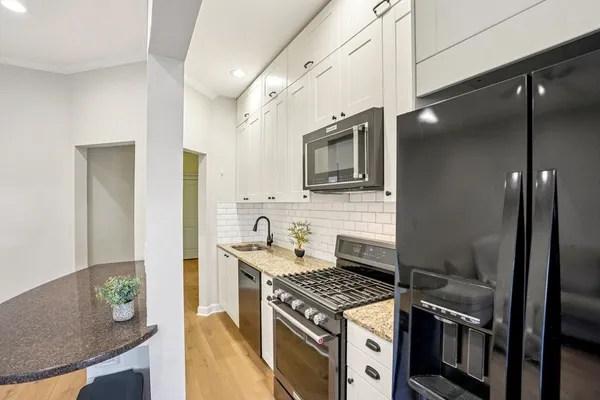 a kitchen with stainless steel appliances granite countertop a stove a sink and a microwave