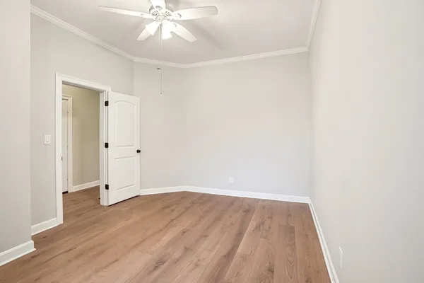 an empty room with wooden floor and a ceiling fan