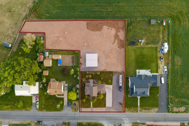681 Island Road Morgan, UT 84050 - Photo 39 of 49 Expansive land parcel featuring a main residence with a dark-pitched roof, a large gravel lot, a substantial open-sided structure, a secondary residence with a light-colored roof, and a well-maintained lawn