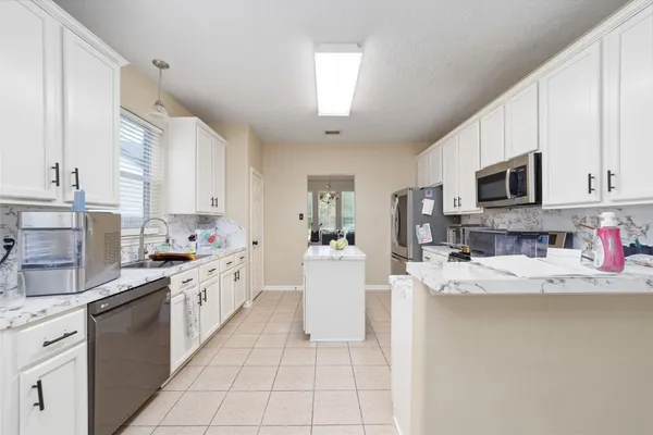 a kitchen with stainless steel appliances granite countertop a sink dishwasher stove top oven and cabinets