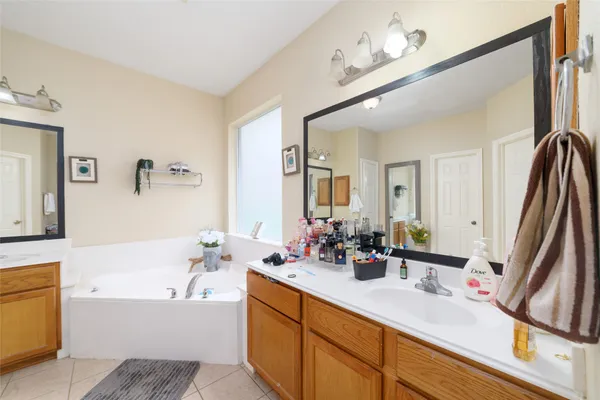 a bathroom with a double vanity sink a mirror and a bathtub