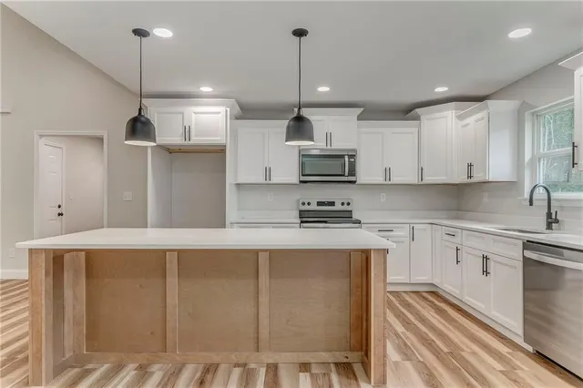 a kitchen with stainless steel appliances granite countertop a sink a stove and a wooden floors