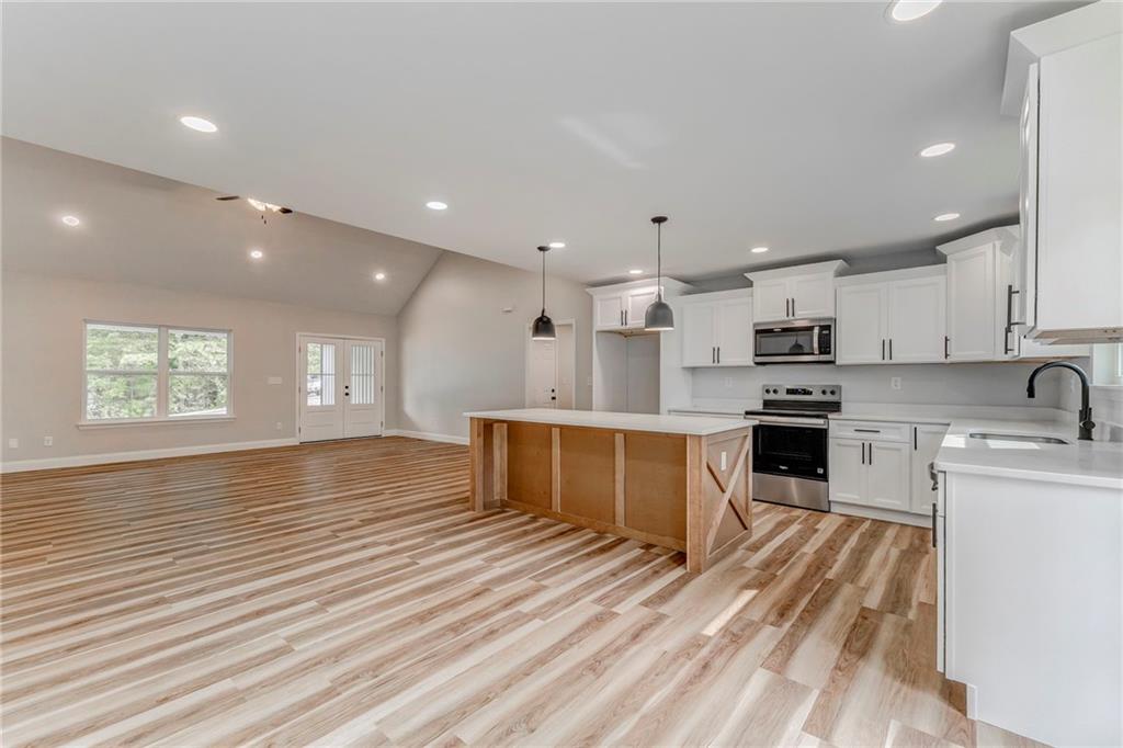 22 Earls Way Chatsworth, GA 30705 - Photo 39 of 64 a large kitchen with stainless steel appliances kitchen island granite countertop a stove a sink a refrigerator and white cabinets with wooden floor