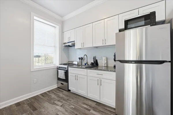a kitchen with stainless steel appliances granite countertop a refrigerator sink and white cabinets
