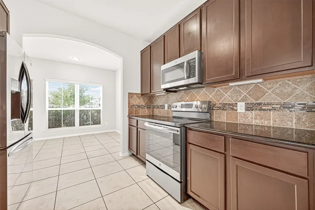 a kitchen with stainless steel appliances granite countertop a stove a sink and a microwave