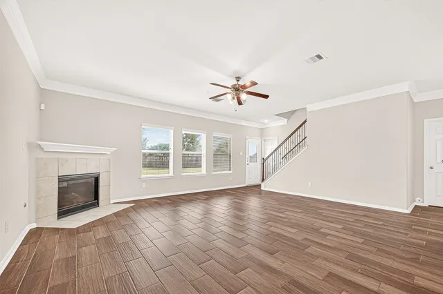 a view of empty room with wooden floor and fan