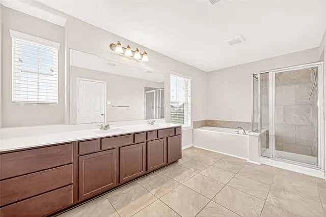 a spacious bathroom with a double vanity sink a large mirror and a bathtub