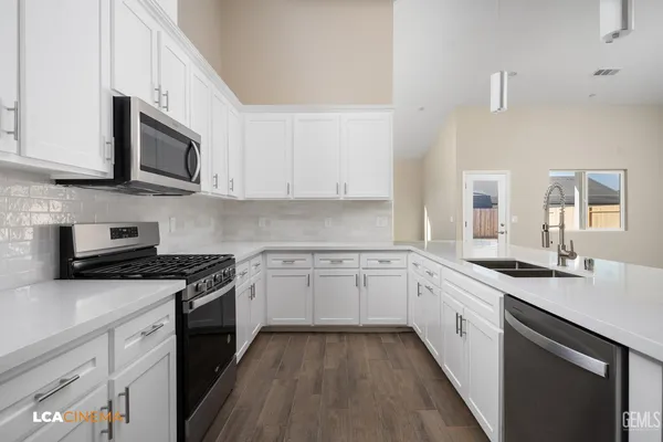 a kitchen with stainless steel appliances granite countertop a sink dishwasher stove and oven with wooden floor