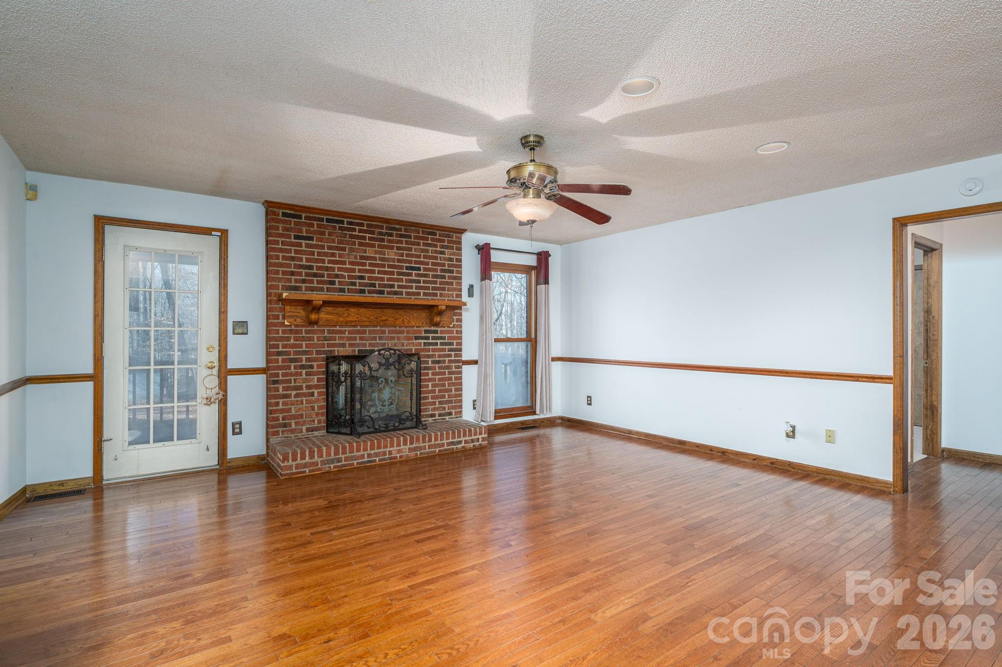 480 South Ingleside Farm Road Iron Station, NC 28080 - Photo 6 of 42 an empty room with wooden floor fireplace and windows