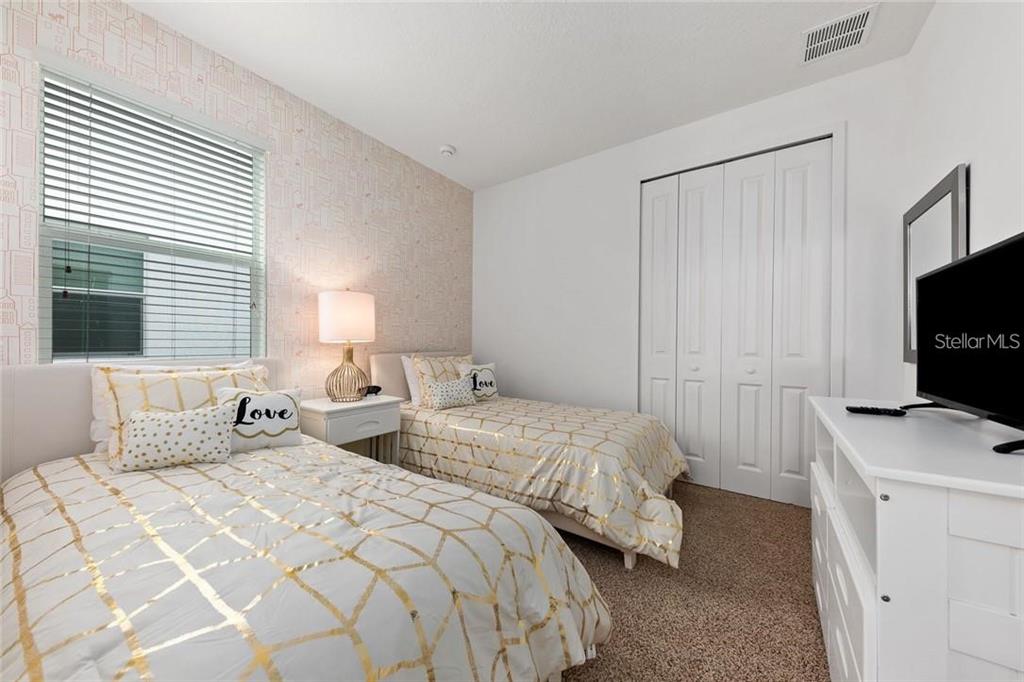 2626 Calistoga Avenue Kissimmee, FL 34741 - Photo 27 of 43 a bedroom with two bed and a flat tv screen on a dresser