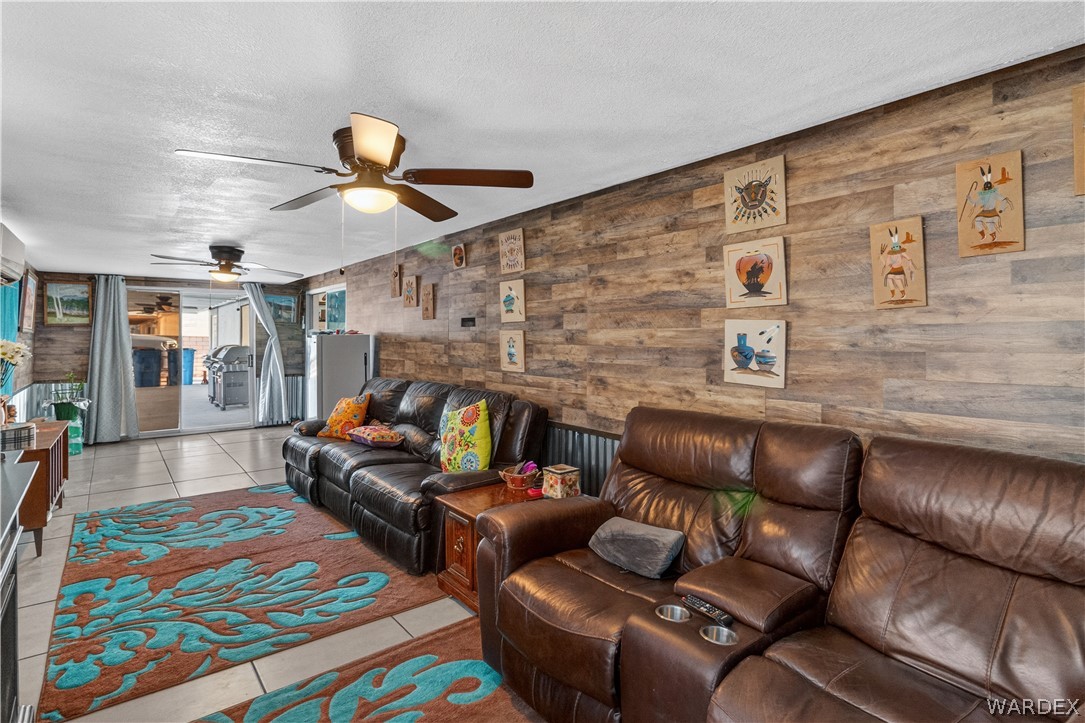 784 Pegasus Ranch Road Bullhead City, AZ 86429 - Photo 53 of 100 Living area featuring wood-finish accent wall, tile flooring, and ceiling fan with integrated lighting
