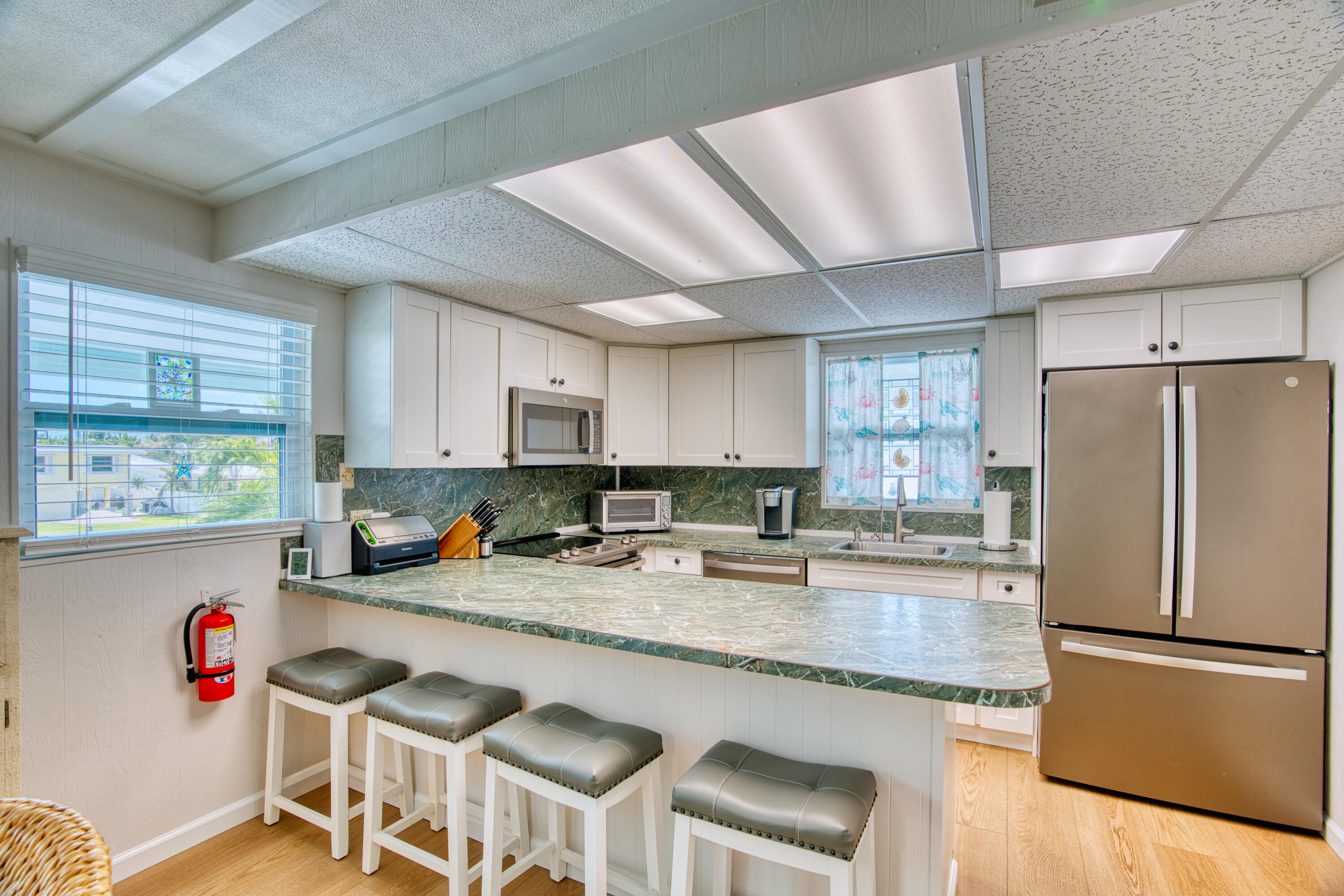 330-340 4th Street Key Colony Beach, FL 33051 - Photo 21 of 68 a kitchen with stainless steel appliances granite countertop a refrigerator a stove a sink dishwasher and white cabinets with wooden floor