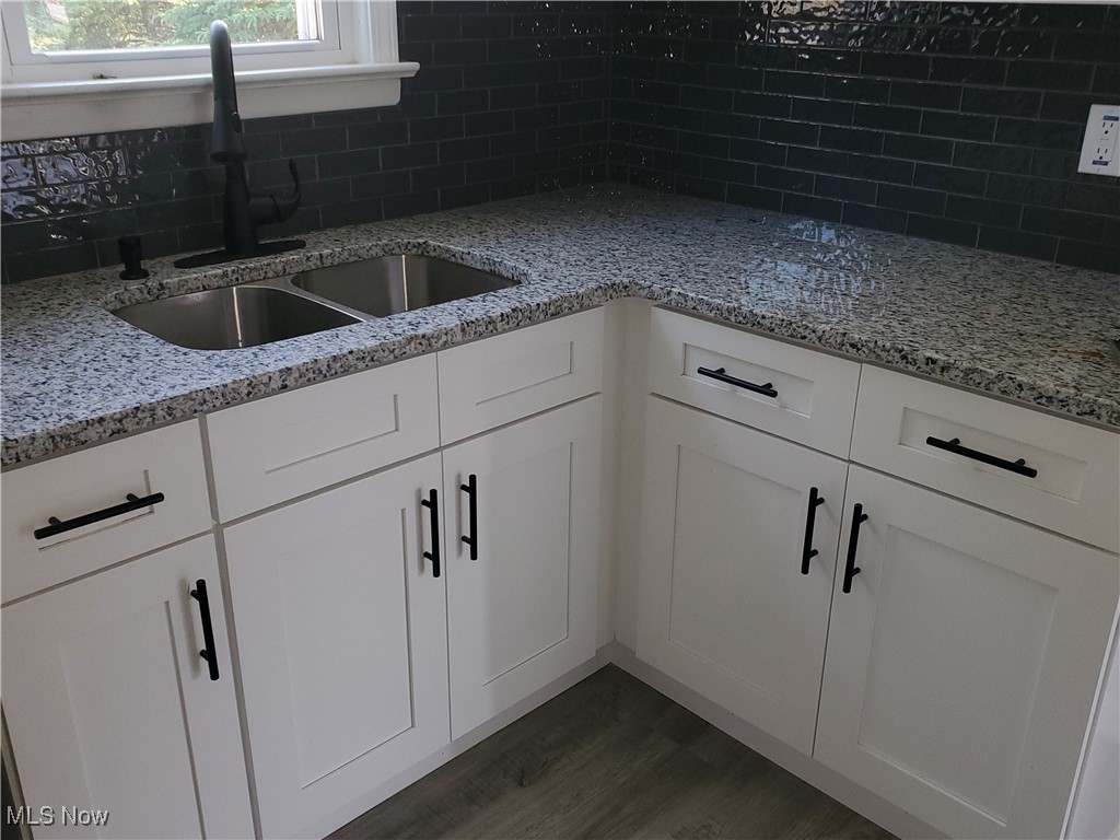 7007 Biddulph Road Brooklyn, OH 44144 - Photo 4 of 16 Kitchen with a sink, tasteful backsplash, dark wood-type flooring, white cabinetry, and light stone countertops