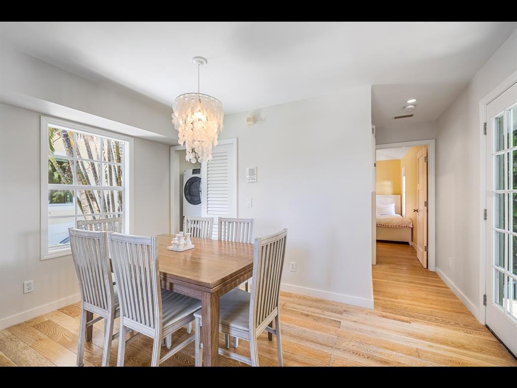 2021 20th Street West Boca Grande, FL 33921 - Photo 48 of 66 a dining room with wooden floor a chandelier a wooden table and chairs
